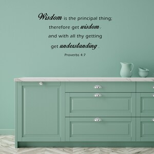 May include: A teal green kitchen with a white countertop and cabinets. The wall is painted a light teal green and features a black vinyl wall decal with the quote "Wisdom is the principal thing; therefore get wisdom. and with all thy getting get understanding. Proverbs 4:7".