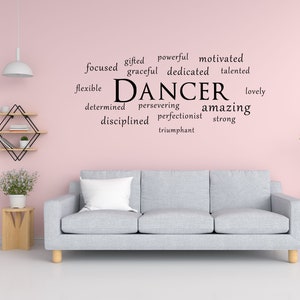 May include: A pink wall with a grey sofa and a word art decal that says "DANCER" with a list of positive words describing a dancer, such as "gifted", "powerful", "motivated", "focused", "graceful", "dedicated", "talented", "flexible", "determined", "persevering", "amazing", "disciplined", "perfectionist", "strong", "lovely", and "triumphant".