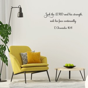 May include: A yellow armchair with two pillows sits in a living room with a white wall. The wall has a black and white inspirational quote that reads "Seek the LORD and his strength, seek his face continually. I Chronicles 16-11".