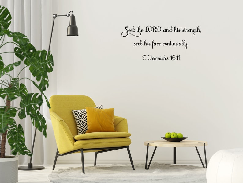 May include: A yellow armchair with two pillows sits in a living room with a white wall. The wall has a black and white inspirational quote that reads "Seek the LORD and his strength, seek his face continually. I Chronicles 16-11".