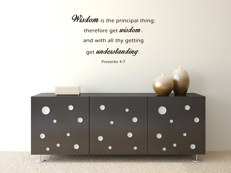May include: A black and white wall decal with the quote "Wisdom is the principal thing; therefore get wisdom: and with all thy getting get understanding. Proverbs 4:7". The decal is displayed on a white wall above a dark brown dresser with white circles.