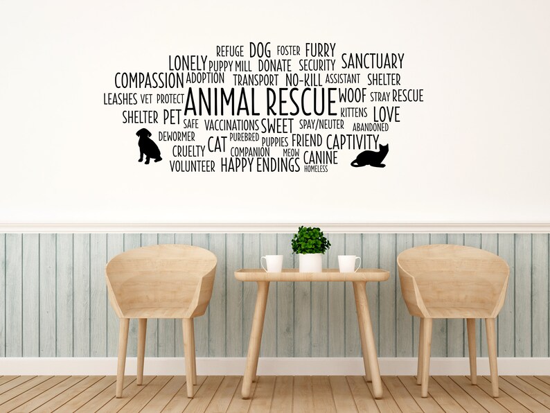 Peut inclure: Un autocollant mural d'art en noir et blanc avec les mots "Animal Rescue" au centre. Les mots sont entour&eacute;s d'autres mots li&eacute;s au sauvetage des animaux, tels que "refuge", "amour", "errant", "compassion", "donner", "b&eacute;n&eacute;vole", "heureux d&eacute;nouement", "accueillir", "poilu", "sanctuaire", "sans euthanasie", "ami", "captivit&eacute;", "canin", "sans abri", "&eacute;levage de chiots", "transport", "laisses", "v&eacute;t&eacute;rinaire", "prot&eacute;ger", "s&ucirc;r", "vaccinations", "doux", "st&eacute;rilisation/castration", "abandonn&eacute;", "cruaut&eacute;", "chat", "compagnon", "pur-sang", "chiots", "chaton", "aboiement", "vermifuge", "miaulement". L'autocollant est sur un mur blanc avec deux chaises en bois et une table devant.