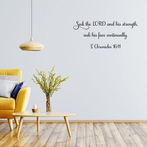 May include: A yellow couch with pillows in a living room setting with a wooden coffee table and a vase of yellow flowers. The wall has a black and white wall decal with the text "Seek the LORD and his strength, seek his face continually. I Chronicles 16-11".