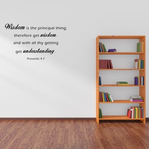 May include: A white wall with a wooden bookshelf filled with books. The wall has a black text quote that reads "Wisdom is the principal thing; therefore get wisdom and with all thy getting get understanding. Proverbs 4:7"