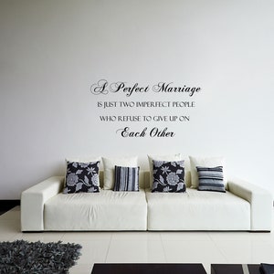 May include: A white couch with black and white patterned throw pillows in a living room with a white wall and a quote that reads "A Perfect Marriage is just two imperfect people who refuse to give up on each other."