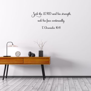 May include: A white wall with a black cursive quote that reads "Seek the LORD and his strength, seek his face continually. I Chronicles 16-11". The wall is decorated with a wooden table, a lamp, and a vase with branches.