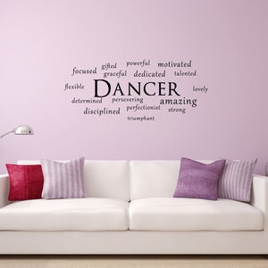 May include: A white sofa with two cushions, one purple and one striped, in a room with a light purple wall. The wall has a black word art decal that says "DANCER" surrounded by words describing the qualities of a dancer, such as "gifted", "powerful", "motivated", "graceful", "dedicated", "talented", "flexible", "determined", "persevering", "amazing", "disciplined", "perfectionist", "strong", "lovely", and "triumphant".
