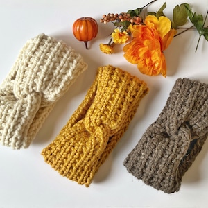 May include: Three knitted headbands in different colors: cream, mustard yellow, and brown. The headbands are made with a chunky yarn and have a knotted design.
