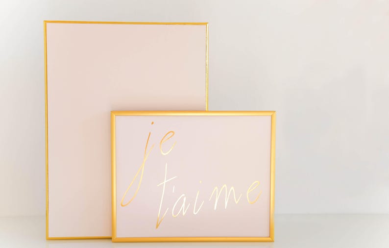 Puede incluir: Dos cuadros con marco dorado y fondo rosa claro. El cuadro m&aacute;s peque&ntilde;o tiene el texto "je t'aime" escrito en letras doradas.