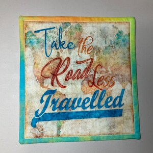 May include: A decorative fabric square with a vintage world map background and the text "Take the Road Less Travelled" in blue and red lettering.