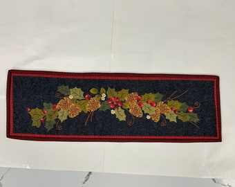 22” x 7” rectangular table topper with an arrangement of holly leaves, berries, and pinecones