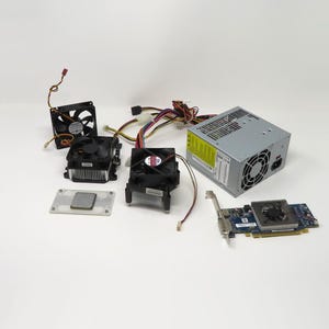 May include: An assortment of computer components, including a power supply, several CPU coolers with fans, and a graphics card. The components are arranged on a white surface, showcasing the internal parts of a computer.