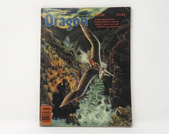 Può includere: Copertina della rivista Dragon #124 con un'illustrazione fantasy di una creatura alata che vola sopra una cascata in un ambiente boschivo.