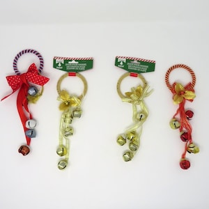 May include: Four Christmas door hangers with bells and ribbon. Each hanger has a different color ribbon and bell combination. The hangers are made of rope and have a gold ring at the top.