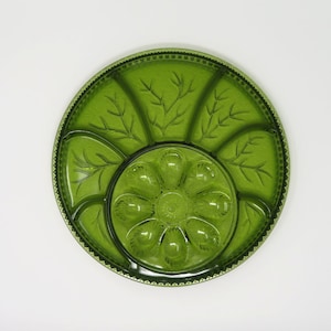 May include: A green glass serving dish with a central flower-shaped section and six smaller sections around the edge. The dish has a decorative etched design.