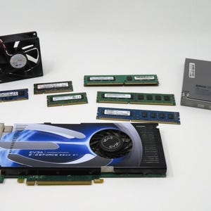 May include: A collection of computer hardware components including a graphics card, RAM modules, a cooling fan, and a DVD drive. The graphics card is a blue and black EVGA GeForce 8800 GT.