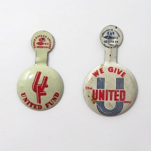 May include: Two vintage metal pinback buttons. One button has a red "UF" logo with "UNITED FUND" text. The other button has "WE GIVE the UNITED way" text. Both buttons have a cream-colored background and a small tab at the top.