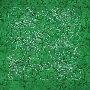 May include: A green fabric square with white stitching in a swirling pattern. The stitching creates a design of leaves and swirls.