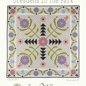 May include: A square quilt titled "Dresdens In The Park" with a floral design. The quilt features a cream background with a repeating dot pattern. The design includes pink, purple, and blue flowers, black triangles, and green stems. The quilt measures 52.5 inches by 52.5 inches.