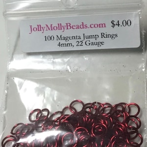 May include: A clear plastic bag containing 100 magenta jump rings. The label reads "JollyMollyBeads.com" and specifies the rings are 4mm and 22 gauge. The jump rings are a deep, reddish-purple color.