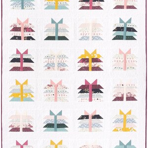 May include: A quilt with a white background and a pattern of colorful stacked triangles. The triangles are made of different fabrics with floral patterns and solid colors, including pink, yellow, green, and burgundy.