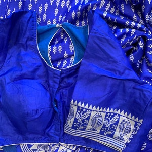 May include: A royal blue silk saree with a white printed design of leaves and fish. The saree has a matching blue blouse with a white trim.