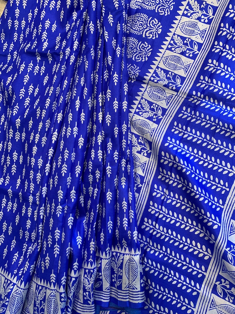 May include: A blue and white cotton saree with a traditional block print design. The saree features a repeating pattern of leaves and fish.