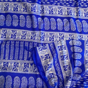 May include: A blue fabric with a white paisley pattern. The fabric has a repeating pattern of paisley shapes, leaves, and fish.