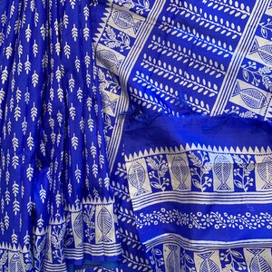 May include: A blue and white cotton saree with a traditional block print design. The saree features a repeating pattern of leaves and fish.