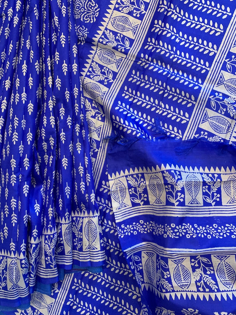 May include: A blue and white cotton saree with a traditional block print design. The saree features a repeating pattern of leaves and fish.