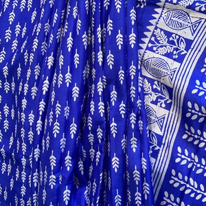 May include: A blue fabric with a white leaf pattern. The fabric has a white border with a geometric design and a fish pattern.