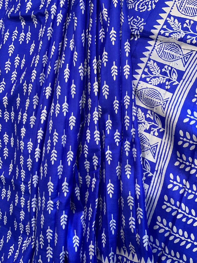 May include: A blue fabric with a white leaf pattern. The fabric has a white border with a geometric design and a fish pattern.