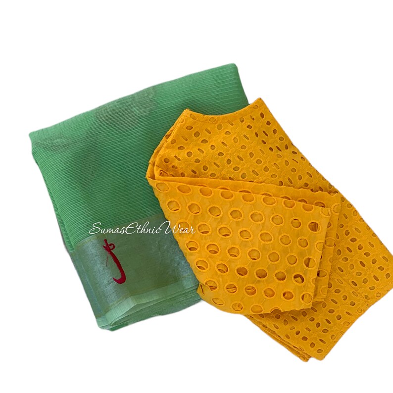 May include: A yellow cotton blouse with a circular cut-out pattern and a green sheer fabric saree. The saree has the text "Sumas Ethnic Wear" embroidered on it.