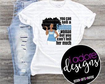 May include: White t-shirt with a graphic design of a Black woman with an afro, wearing a blue tank top and white pants. The text "You can tell a Spelman woman but you can't tell her much" is printed on the shirt. The year 1881 is printed on the woman's tank top. The graphic is surrounded by a black circle with the text "i adore designs" in pink letters. The text "DESIGN GIFTS PAPERIE" is printed below the circle.