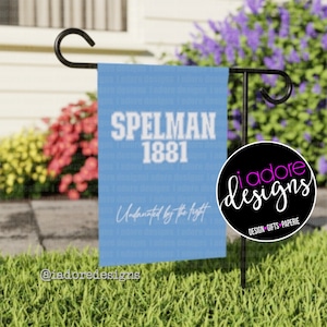 Könnte beinhalten: Eine blaue Gartenflagge mit weißem Text, der "SPELMAN 1881" und "Undaunted by the fight" lautet.