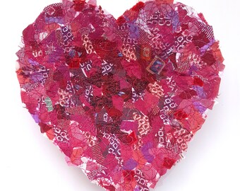 Puede incluir: Una pieza de arte en forma de corazón hecha de retazos de tela roja, rosa y morada cosidos juntos.