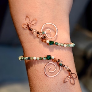 May include: A copper wire bracelet with green and white agate beads, copper swirls, and copper flower accents.