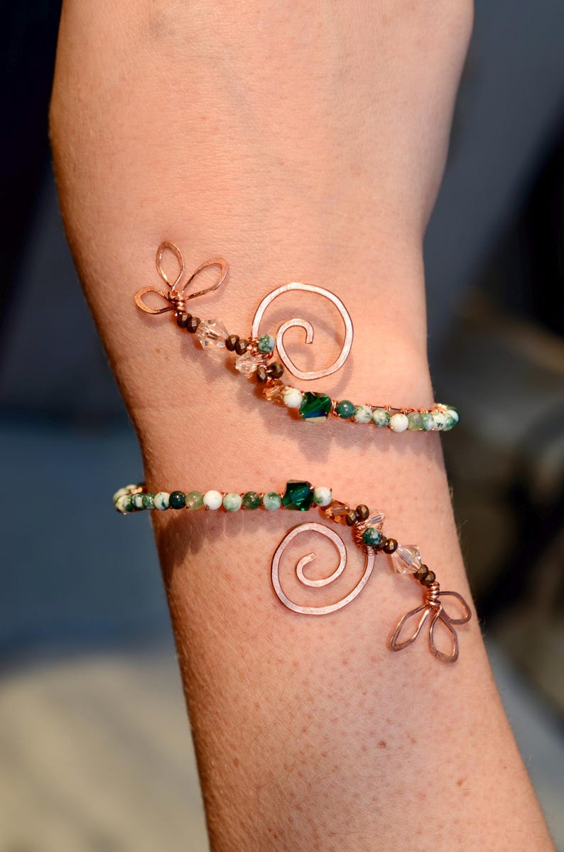 May include: A copper wire bracelet with green and white agate beads, copper swirls, and copper flower accents.