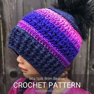 Op de afbeelding: Een gebreide muts met een gespleten rand in tinten roze, paars en blauw met een zwarte pompon bovenop. De muts is gemaakt van glinsterend garen. De tekst "Mia Split Brim Beanie CROCHET PATTERN WWW.DENIMADE.COM" staat onderaan de afbeelding.