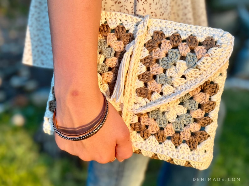 May include: A crocheted clutch bag with a granny square pattern in shades of brown, beige, and blue. The bag has a white tassel.