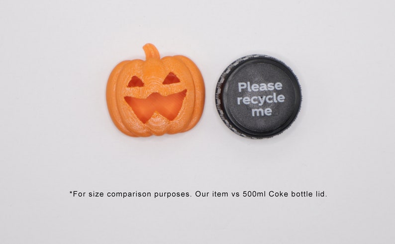 May include: An orange plastic jack-o'-lantern with a carved face, next to a black plastic bottle cap with the text "Please recycle me".