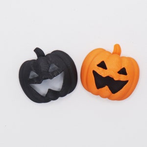 May include: Two Halloween jack-o'-lantern decorations. One is black and the other is orange.