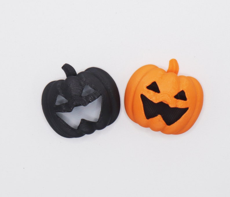 May include: Two Halloween jack-o'-lantern decorations. One is black and the other is orange.