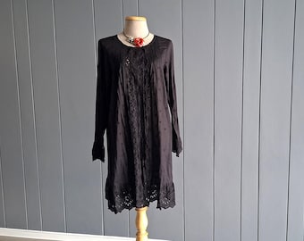 May include: A dark brown long-sleeved tunic dress featuring a round neckline, vertical pintuck detailing on the chest, and intricate floral embroidery running down the center. The hem and sleeve cuffs are finished with a scalloped eyelet lace trim.