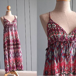 May include: A red, blue, and white patterned maxi dress with a V-neck and spaghetti straps. The dress has a tiered skirt and a relaxed fit.