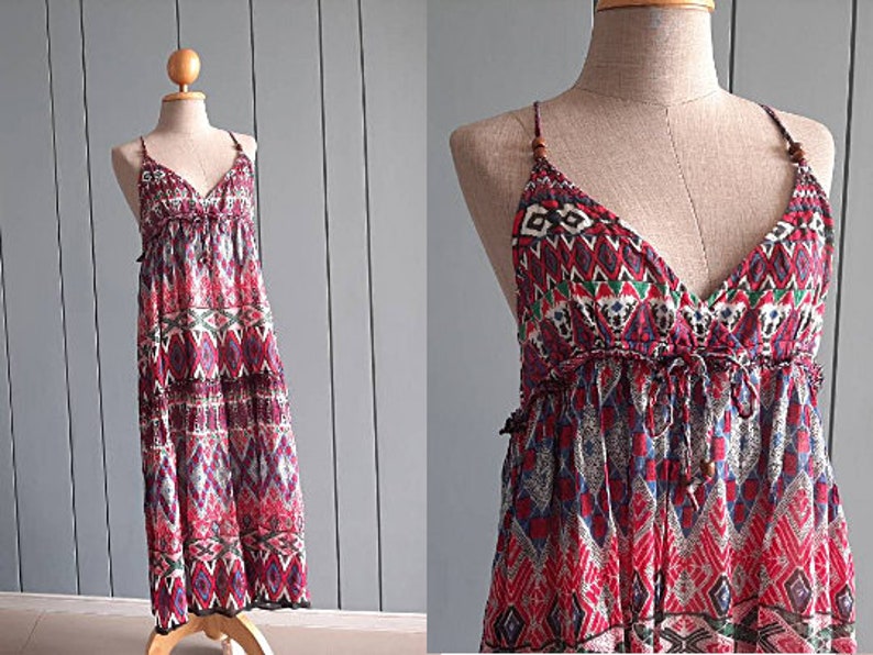 May include: A red, blue, and white patterned maxi dress with a V-neck and spaghetti straps. The dress has a tiered skirt and a relaxed fit.