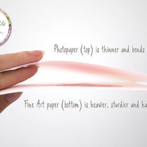 May include: A hand holds two pieces of paper, one on top of the other. The top piece of paper is photo paper, which is thinner and bends easily. The bottom piece of paper is fine art paper, which is heavier, sturdier, and hardly bends. The text "Photopaper (top) is thinner and bends easily." and "Fine Art paper (bottom) is heavier, sturdier and hardly bends." is written below the paper.