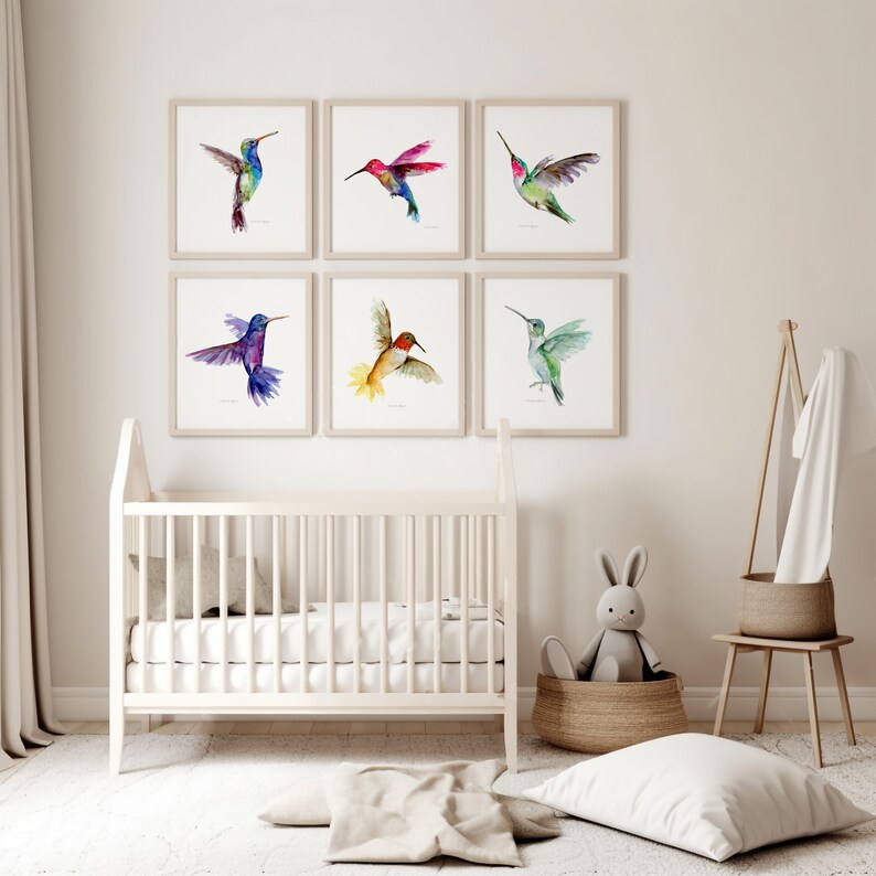 Puede incluir: Seis pinturas de acuarela enmarcadas de colibr&iacute;es en varios colores, incluyendo azul, verde, rojo y amarillo. Las pinturas est&aacute;n dispuestas en una cuadr&iacute;cula en una pared blanca.