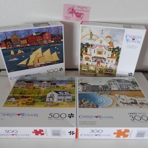 May include: Four jigsaw puzzles with colorful illustrations. Two puzzles are 500 pieces, and one is 300 pieces. The puzzle images depict coastal scenes with boats, buildings, and landscapes. The puzzles are by Charles Wysocki.