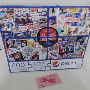 May include: A Pepsi-Cola 500-piece puzzle multipack with a collage of vintage Pepsi advertisements. The box features the Pepsi logo and the words "Have a Pepsi Day!" in a retro design. A poster is included.